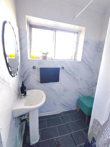 a white bathroom with a sink and a window at Hospedaje Luna in Valdivia