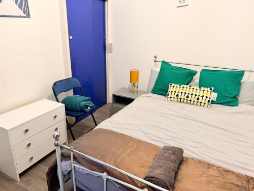 a bedroom with a bed with green pillows and a chair at Smart Double Room in Reading