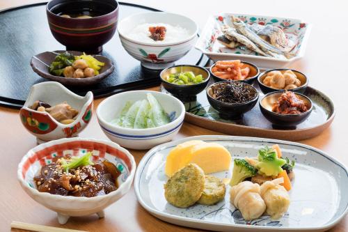 a table with plates of food and bowls of food at Miyako Resort Okushima Aqua Forest in Shima