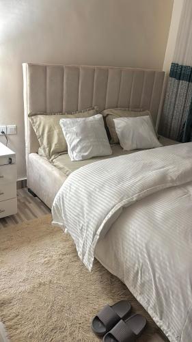 a bedroom with a white bed with a gray headboard at Amber Home Kigali in Kigali