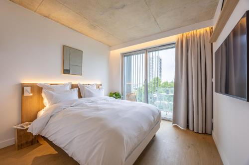 a bedroom with a white bed and a large window at BABEL COMMUNITY Hôtel Bordeaux in Bordeaux