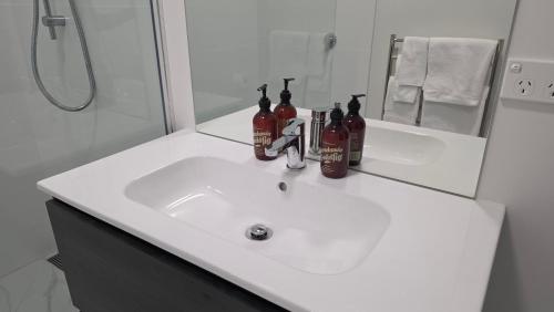 a white bathroom sink with bottles on top of it at Lake Taupo Hotel in Taupo