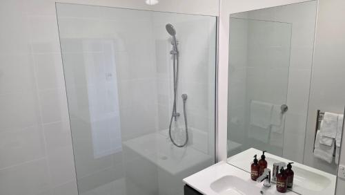 a white bathroom with a shower and a sink at Lake Taupo Hotel in Taupo