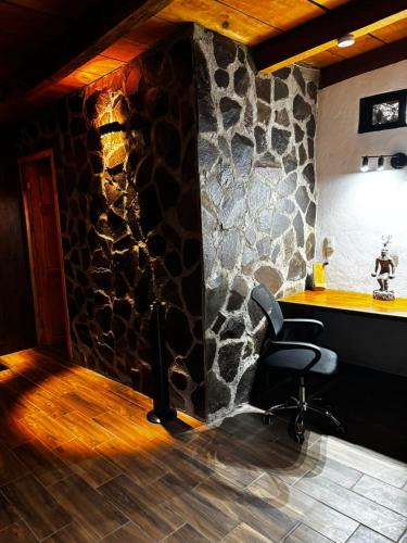 a desk with a chair in a room with a stone wall at Mazamitla Pinos del Rio in Mazamitla