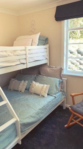 a bedroom with a bunk bed with pillows on it at Sun kissed beach haven in Waitarere