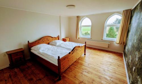 a bedroom with a wooden bed and two windows at Karakul Shepherd House in Tinglev