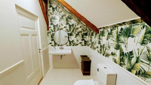 a bathroom with a sink and a leafy wallpaper at Karakul Shepherd House in Tinglev