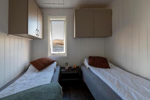 two beds in a small room with a window at Sandhåland Camping Hytte nr 7 in Sandhåland