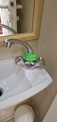 a bathroom sink with a green handle and a faucet at Maisonnette duplex 4 pers proche mer et golf in Talmont