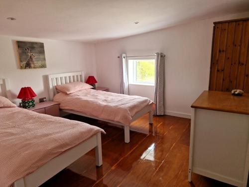 a bedroom with two beds and a window at Mortimers Farm Barn in Saffron Walden