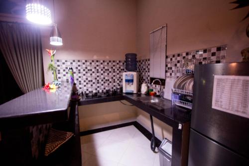 a kitchen with a black counter and a refrigerator at Ratna Villa in Ubud