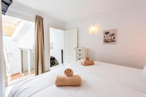 a white bedroom with two towels on a bed at Casa Merlin Capistrano playa in Nerja