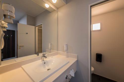 uma casa de banho com um lavatório e um espelho em Best Western Hotel Cologne Airport Troisdorf em Troisdorf