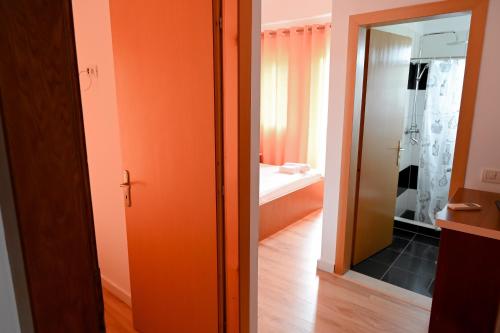 ein Badezimmer mit einer orangefarbenen Tür und einem Spiegel in der Unterkunft Max Kriti Hotel in Shëngjin
