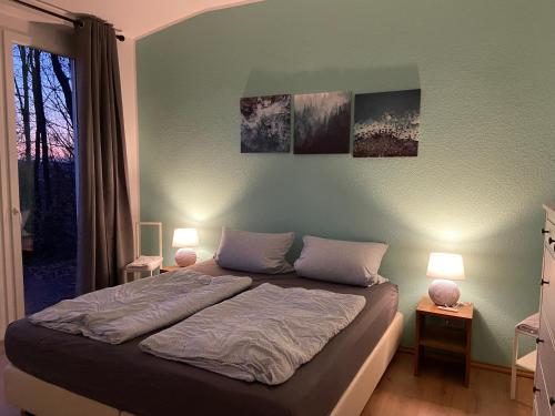 a bedroom with a bed with two lamps and a window at Moderner Bungalow E25 in Lichtenau