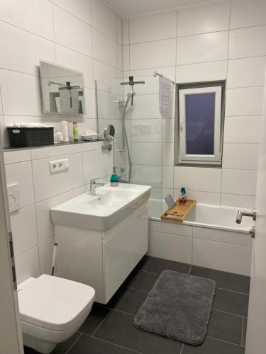 a white bathroom with a toilet and a sink at Moderner Bungalow E25 in Lichtenau
