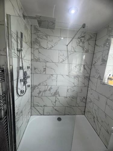 a bathroom with a shower with white marble walls at Central Highland Escape in Caol