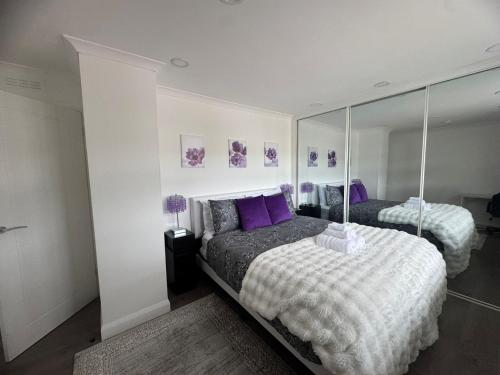 a bedroom with two beds with purple pillows and a mirror at Central Highland Escape in Caol