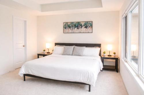 a bedroom with a large white bed and two windows at Spacious 4BR Home with EV Charger in Cambridge