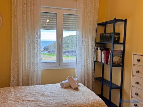 a bedroom with a bed with a window and a book shelf at Apartamento Barro Playa in Barro de Llanes