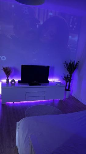 a living room with a laptop on a table with purple lights at Large Studio Near Train station and Disney in Lognes