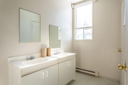 a white bathroom with two sinks and a mirror at Camp Val Notre-Dame in Herouxville