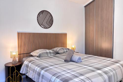 a bed with two pillows and a clock on the wall at Le Cherpin I Duplex charmant in Roanne