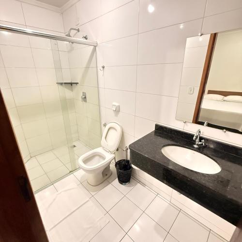 a bathroom with a toilet and a sink and a shower at Hotel Rio Grande in Dourados