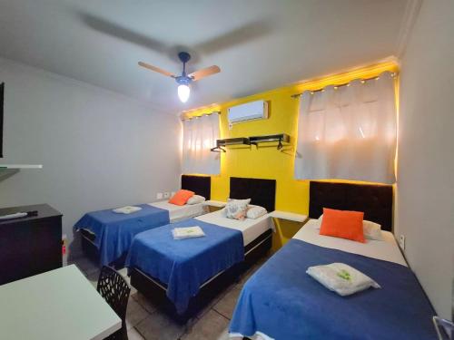 a room with three beds and a ceiling fan at Pousada uberaba in Uberaba