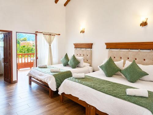 a bedroom with two beds and a balcony at Hotel las Palmas in Villa de Leyva