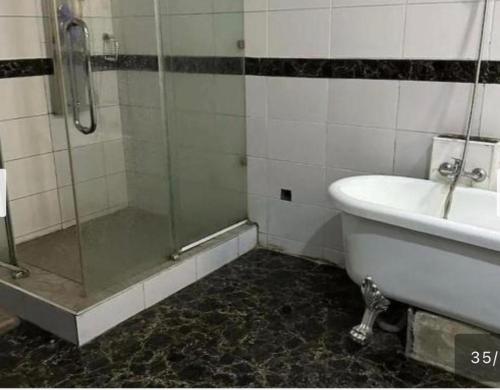 a bathroom with a shower and a tub and a sink at Benyster Hotel in Gwarinpa