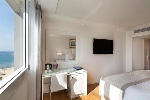 a bedroom with a bed and a desk with a television at Orchid Tel Aviv in Tel Aviv