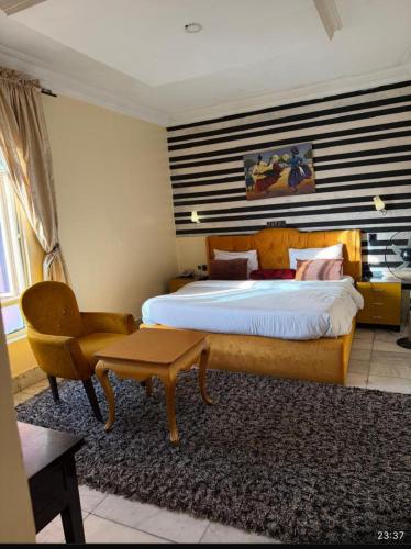 a bedroom with a bed and a desk and a chair at Benyster Hotel in Gwarinpa