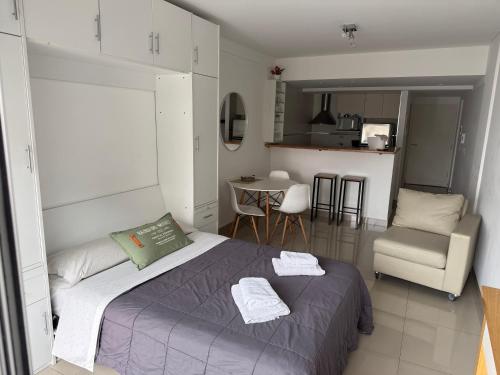 a bedroom with a bed and a chair and a kitchen at Monoambiente con amenities Y MAS in Buenos Aires