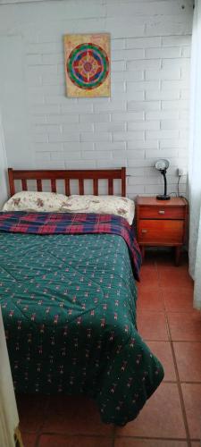 a bed with a green comforter and a side table at Agradable casa al lado de la playa in Las Cruces