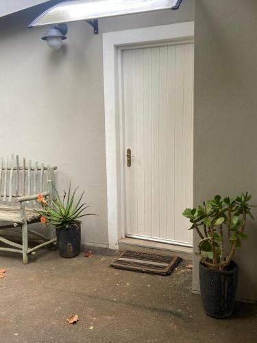 a white garage door with two plants and a bench at Railway Cottage at Rawdons Country Estate in Nottingham Road