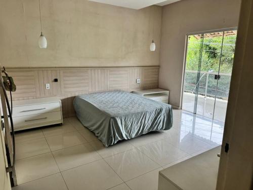 a bedroom with a bed and a large window at Recanto do Galo in Volta Redonda