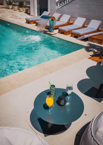 a table with drinks on it next to a swimming pool at Villa JOSANA in Sarandë