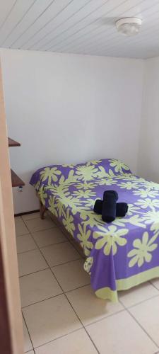 a bedroom with a bed with a purple and white comforter at Heaiti Lodge in Avatoru