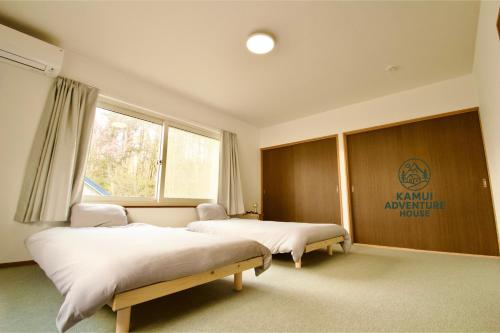 a bedroom with two beds and a window at Kamui Adventure House in Asahikawa