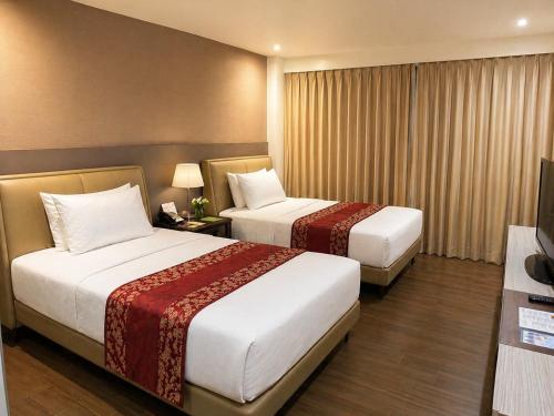 a hotel room with two beds and a television at The E-Hotel Makati in Manila