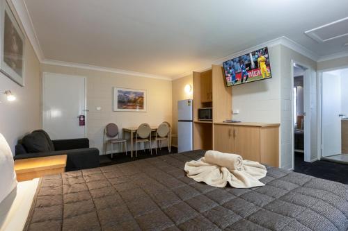 a room with a bed and a kitchen and a living room at All Seasons Motor Lodge in Dubbo
