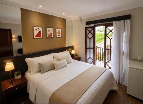 a bedroom with a large bed and a balcony at Luxo no Castelo - Duplex Premium com Lazer total e Piscina aquecida in Campos do Jordão