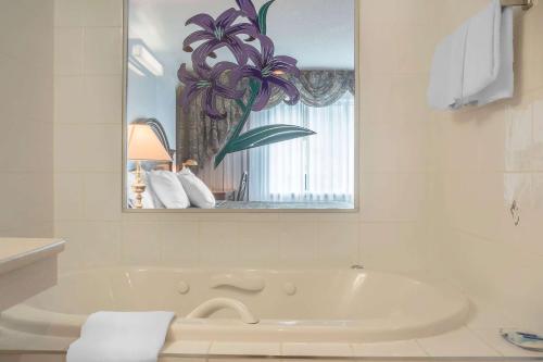 a white bathroom with a tub and a mirror at Rodeway Inn Fallsview in Niagara Falls