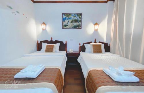 two twin beds in a room with white walls at Khampiane Hotel in Vientiane