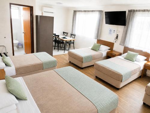 a hotel room with three beds and a table at Cedar Lodge Motel in Townsville