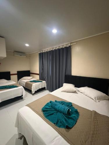 a hotel room with two beds with towels on them at Visk Palace Hotel e Restaurante in Foz do Iguaçu