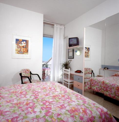 a bedroom with two beds and a desk and a mirror at Hotel Chic in Cattolica