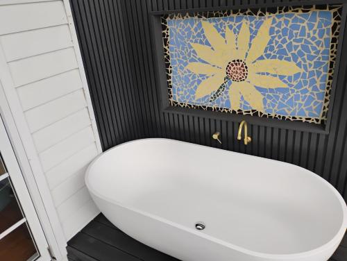 a bathroom with a white sink and a flower curtain at Romantic Ocean View Studio at Stanwell Tops in Stanwell Park