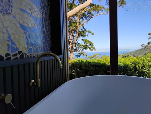 a bath tub in a bathroom with a view of the ocean at Romantic Ocean View Studio at Stanwell Tops in Stanwell Park